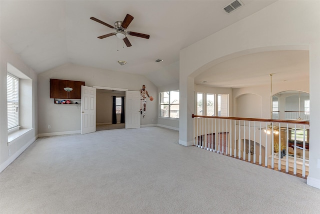 spare room featuring visible vents, light carpet, vaulted ceiling, ceiling fan, and baseboards