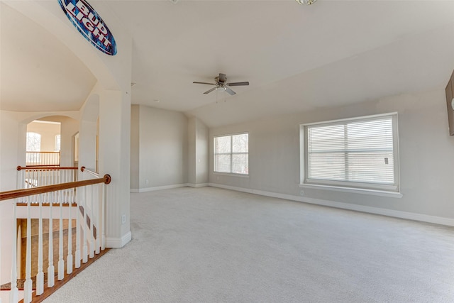 unfurnished room with a ceiling fan, lofted ceiling, light carpet, and baseboards