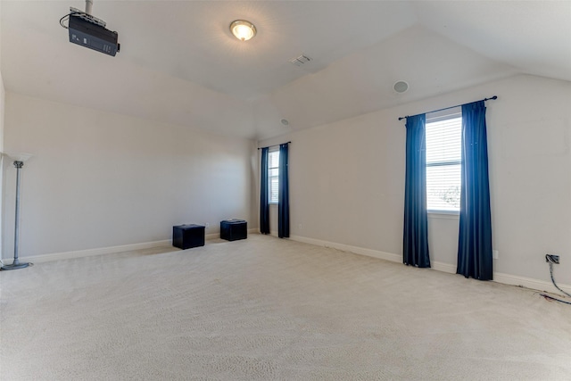 spare room with lofted ceiling, light carpet, and baseboards