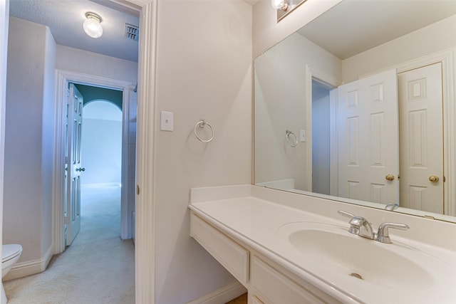 bathroom featuring toilet, baseboards, and vanity