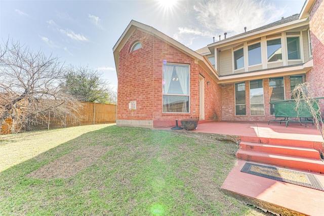 rear view of property with a patio area, fence, a lawn, and brick siding