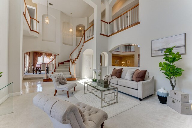 living area with light carpet, baseboards, arched walkways, a towering ceiling, and stairs