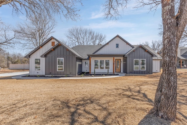 view of front of home featuring board and batten siding, a front yard, and roof with shingles