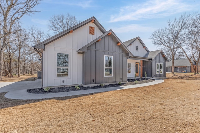 view of front of home with roof with shingles, board and batten siding, and a front yard