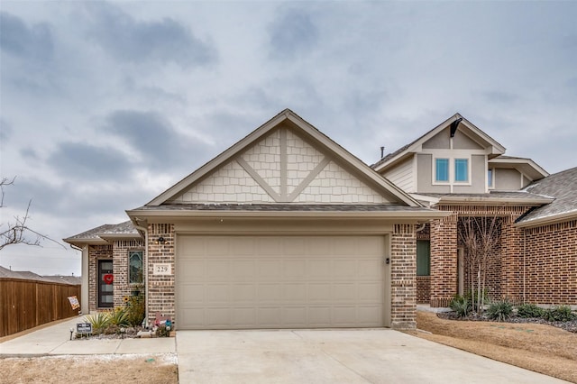 view of front of home with a garage, brick siding, fence, and driveway