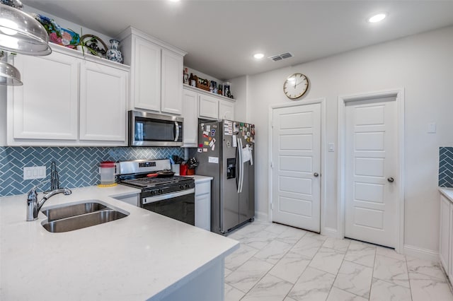 kitchen with marble finish floor, light countertops, appliances with stainless steel finishes, white cabinetry, and a sink