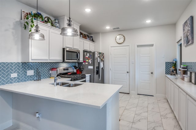 kitchen with a peninsula, marble finish floor, light countertops, hanging light fixtures, and appliances with stainless steel finishes