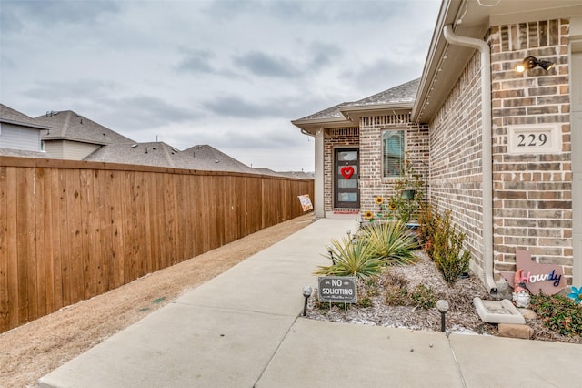 property entrance featuring brick siding and fence