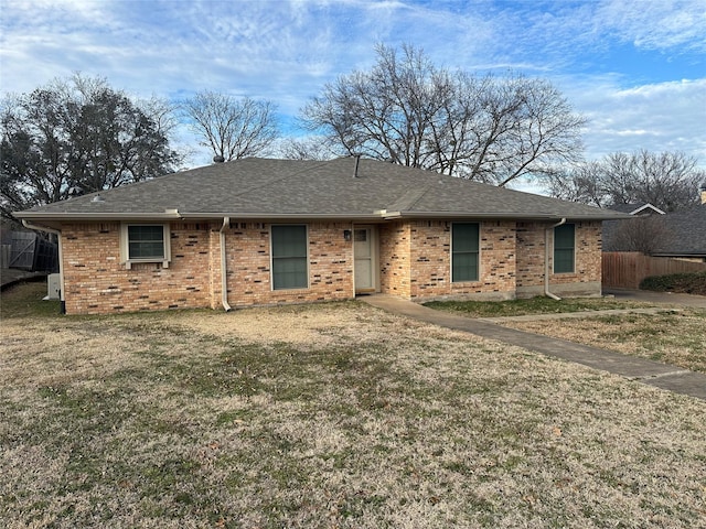 ranch-style house with a shingled roof, a front lawn, and brick siding