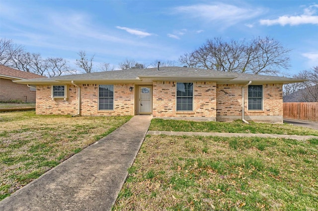 ranch-style house with a front yard, brick siding, and fence