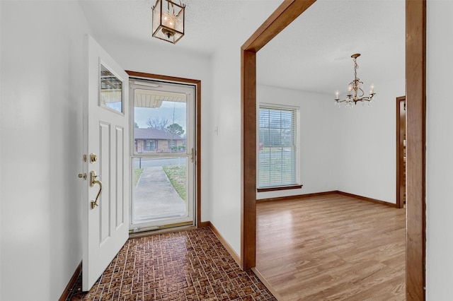 foyer with a healthy amount of sunlight, an inviting chandelier, and baseboards