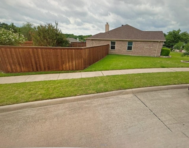 view of home's exterior featuring fence private yard, brick siding, and a yard