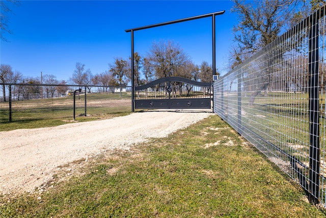 view of road featuring dirt driveway, a gated entry, and a gate