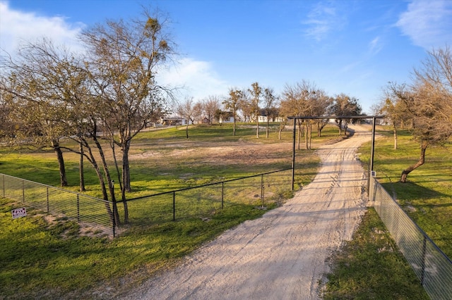 view of home's community with a rural view, a lawn, and fence