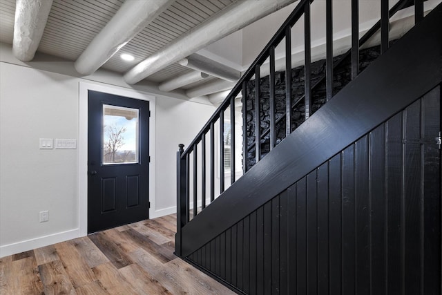 entrance foyer featuring stairway, beamed ceiling, light wood-style flooring, and baseboards