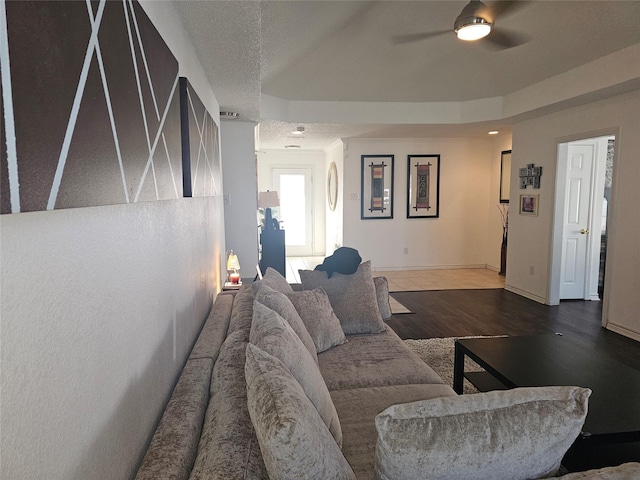 living area featuring baseboards, a textured ceiling, a ceiling fan, and wood finished floors