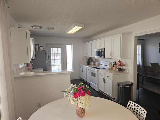 kitchen featuring light countertops, appliances with stainless steel finishes, a peninsula, and white cabinetry