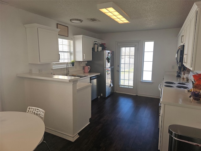 kitchen featuring appliances with stainless steel finishes, dark wood-type flooring, light countertops, a textured ceiling, and white cabinetry