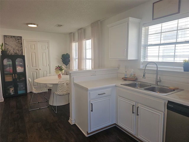 kitchen with a peninsula, stainless steel dishwasher, a sink, and white cabinetry