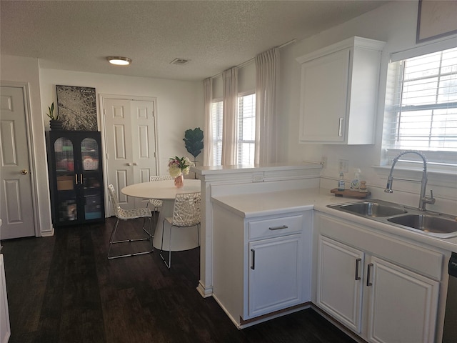 kitchen with a peninsula, a sink, light countertops, and white cabinets