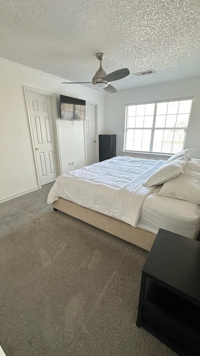 carpeted bedroom with a textured ceiling, ceiling fan, visible vents, and baseboards