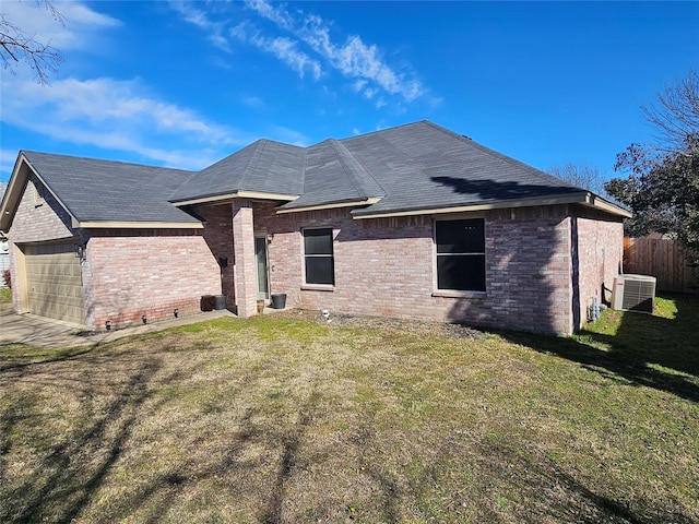 back of property featuring an attached garage, central AC, brick siding, fence, and a lawn