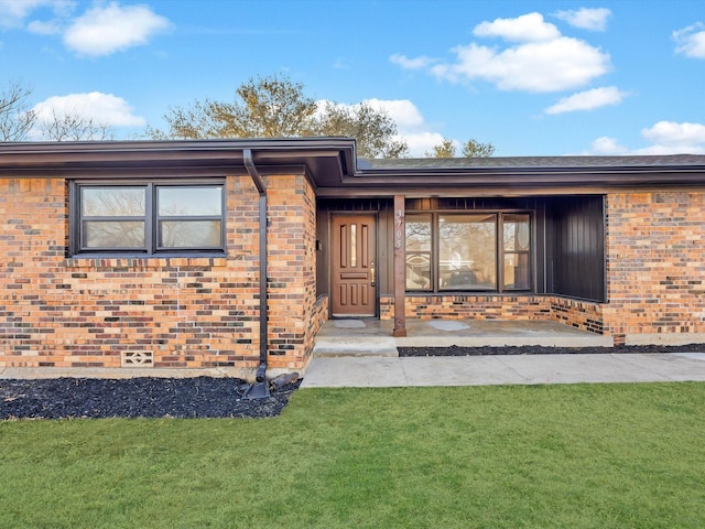 doorway to property with a yard and brick siding