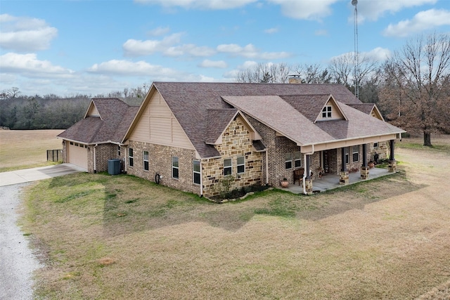 view of front of property featuring roof with shingles, covered porch, an attached garage, a front yard, and driveway