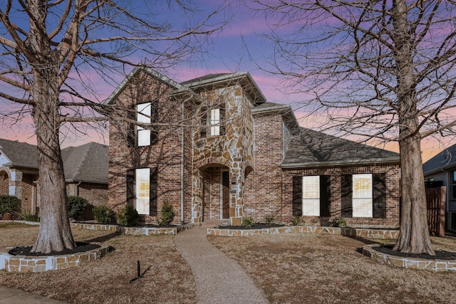 view of front of property with brick siding, stone siding, and roof with shingles