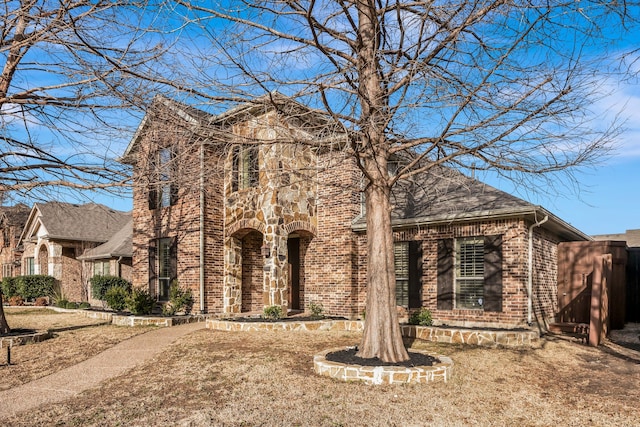 view of front facade featuring brick siding, stone siding, and a shingled roof