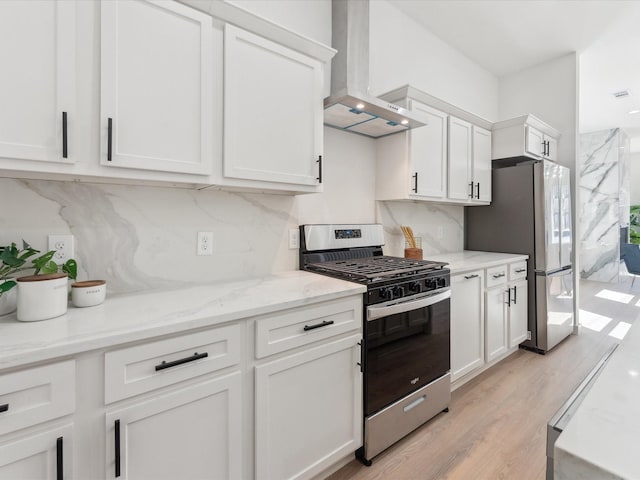 kitchen with stainless steel appliances, wall chimney range hood, and white cabinetry