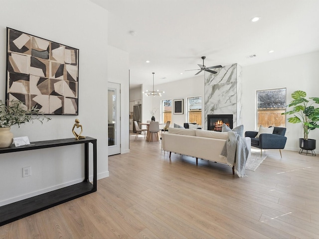 living area featuring baseboards, a premium fireplace, light wood-style flooring, and recessed lighting