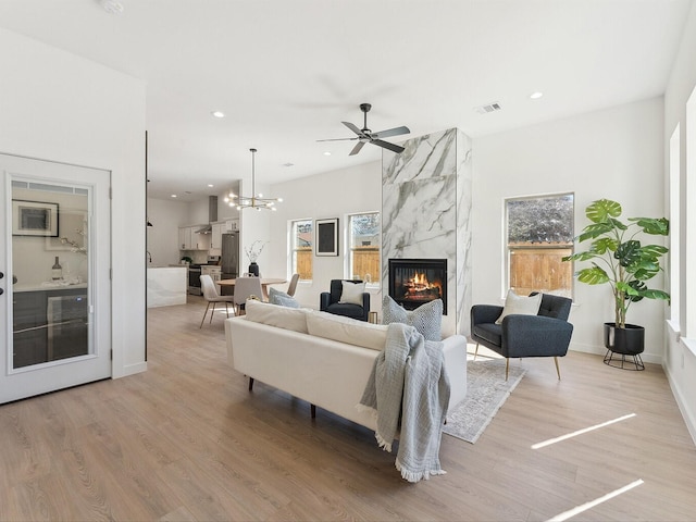 living area featuring light wood-style flooring, recessed lighting, visible vents, a high end fireplace, and a wealth of natural light