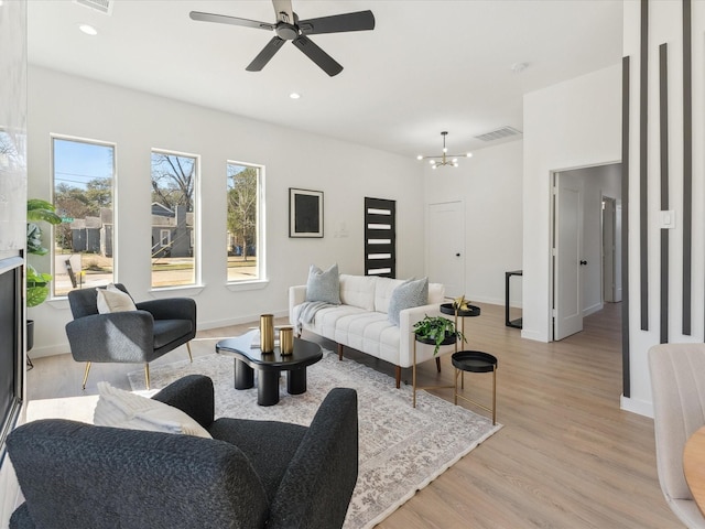 living room with recessed lighting, baseboards, visible vents, light wood-type flooring, and ceiling fan with notable chandelier