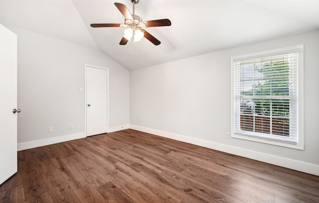 spare room featuring vaulted ceiling, dark wood-style flooring, a ceiling fan, and baseboards