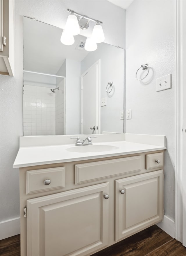 bathroom with visible vents, a shower, wood finished floors, and vanity