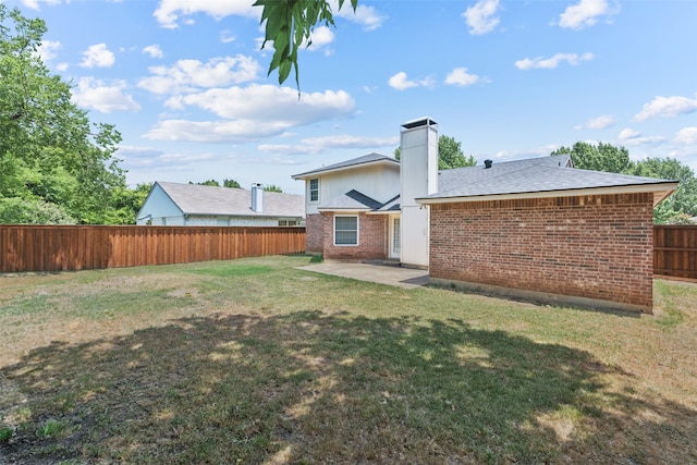 rear view of property featuring a patio area, brick siding, a yard, and a fenced backyard