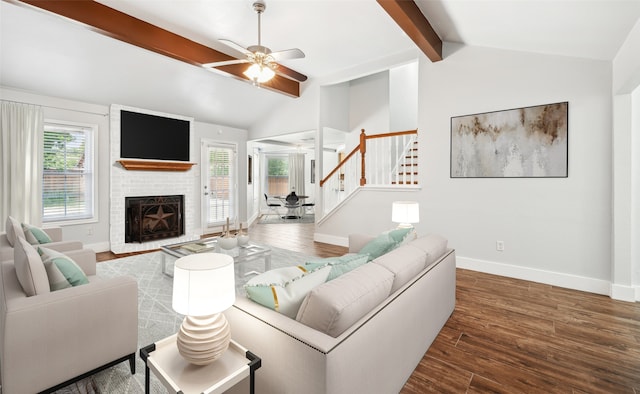 living room with vaulted ceiling with beams, a brick fireplace, baseboards, and wood finished floors