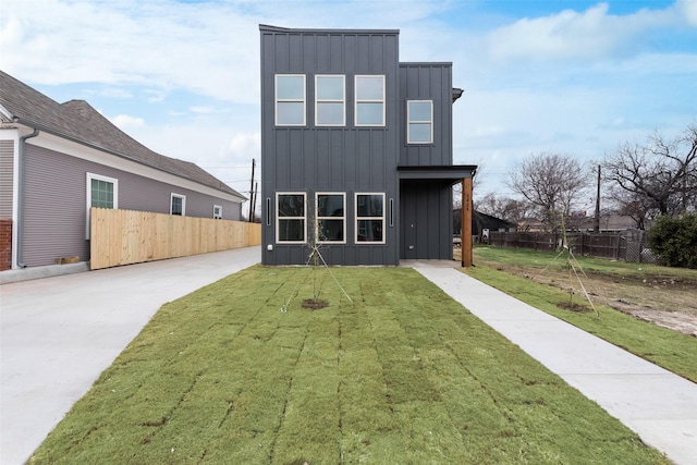 rear view of property featuring a lawn, fence, and board and batten siding