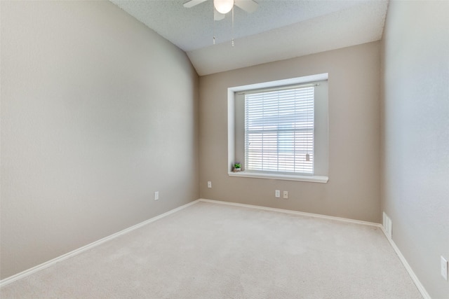 spare room featuring lofted ceiling, light colored carpet, visible vents, baseboards, and a ceiling fan