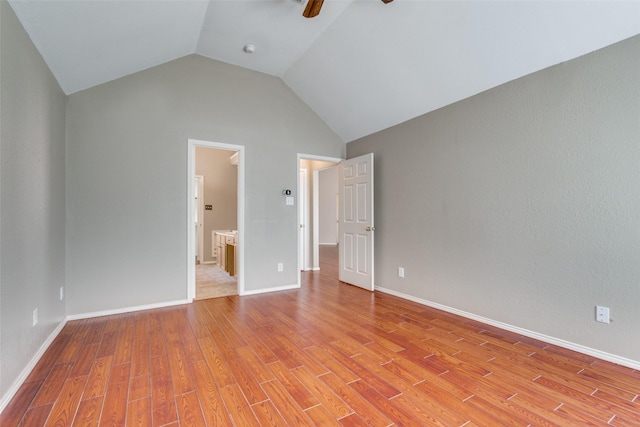 unfurnished bedroom featuring lofted ceiling, light wood finished floors, and baseboards