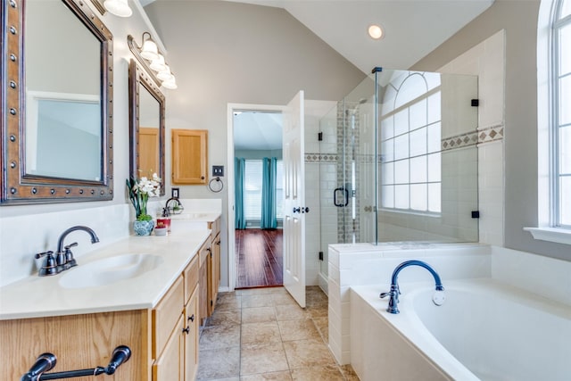 bathroom featuring lofted ceiling, double vanity, a sink, and a bath