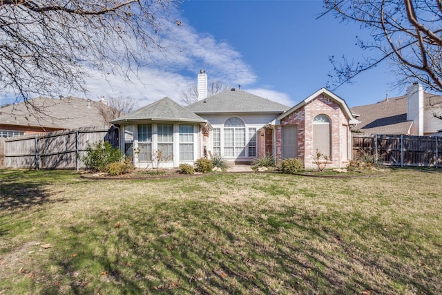 back of property with a yard, brick siding, fence, and a chimney