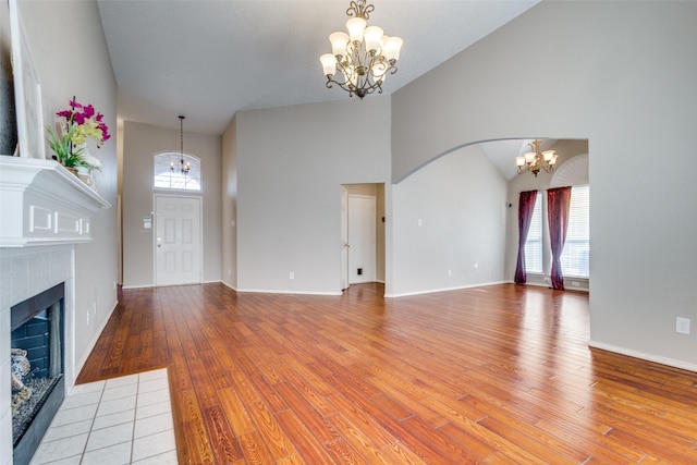 unfurnished living room featuring light wood-type flooring, an inviting chandelier, a fireplace, and a healthy amount of sunlight