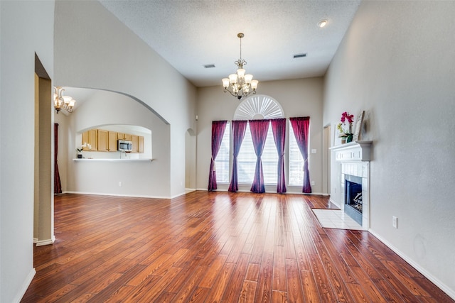 unfurnished living room with baseboards, a fireplace, wood finished floors, and an inviting chandelier