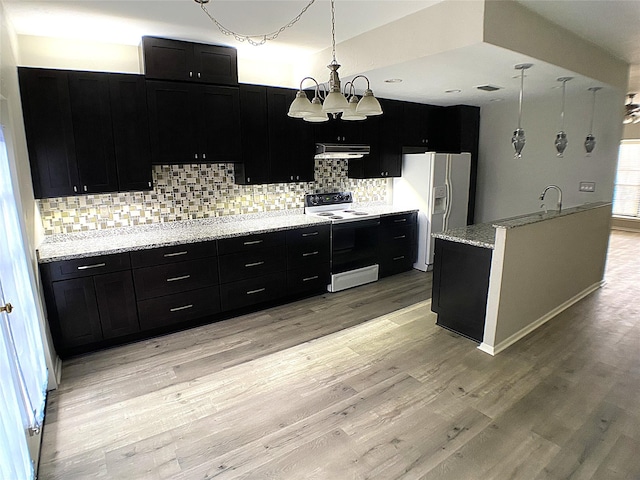 kitchen featuring under cabinet range hood, electric range, white refrigerator with ice dispenser, light wood-style floors, and dark cabinetry