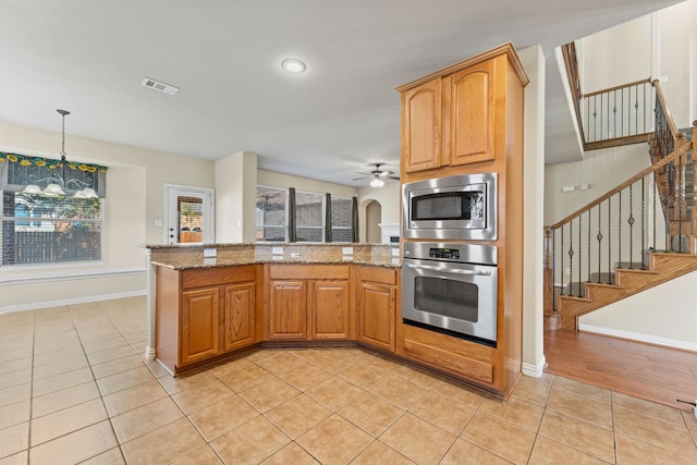 kitchen featuring light tile patterned floors, visible vents, hanging light fixtures, light stone countertops, and stainless steel appliances