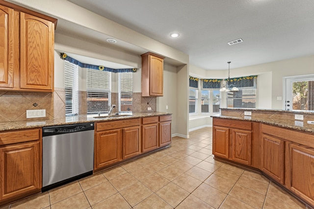 kitchen featuring light stone counters, visible vents, hanging light fixtures, stainless steel dishwasher, and a sink