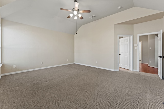 spare room featuring vaulted ceiling, carpet flooring, visible vents, and a ceiling fan