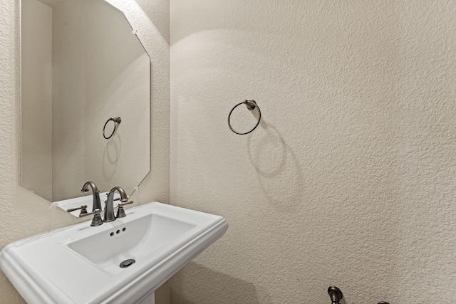 bathroom featuring a textured wall and a sink